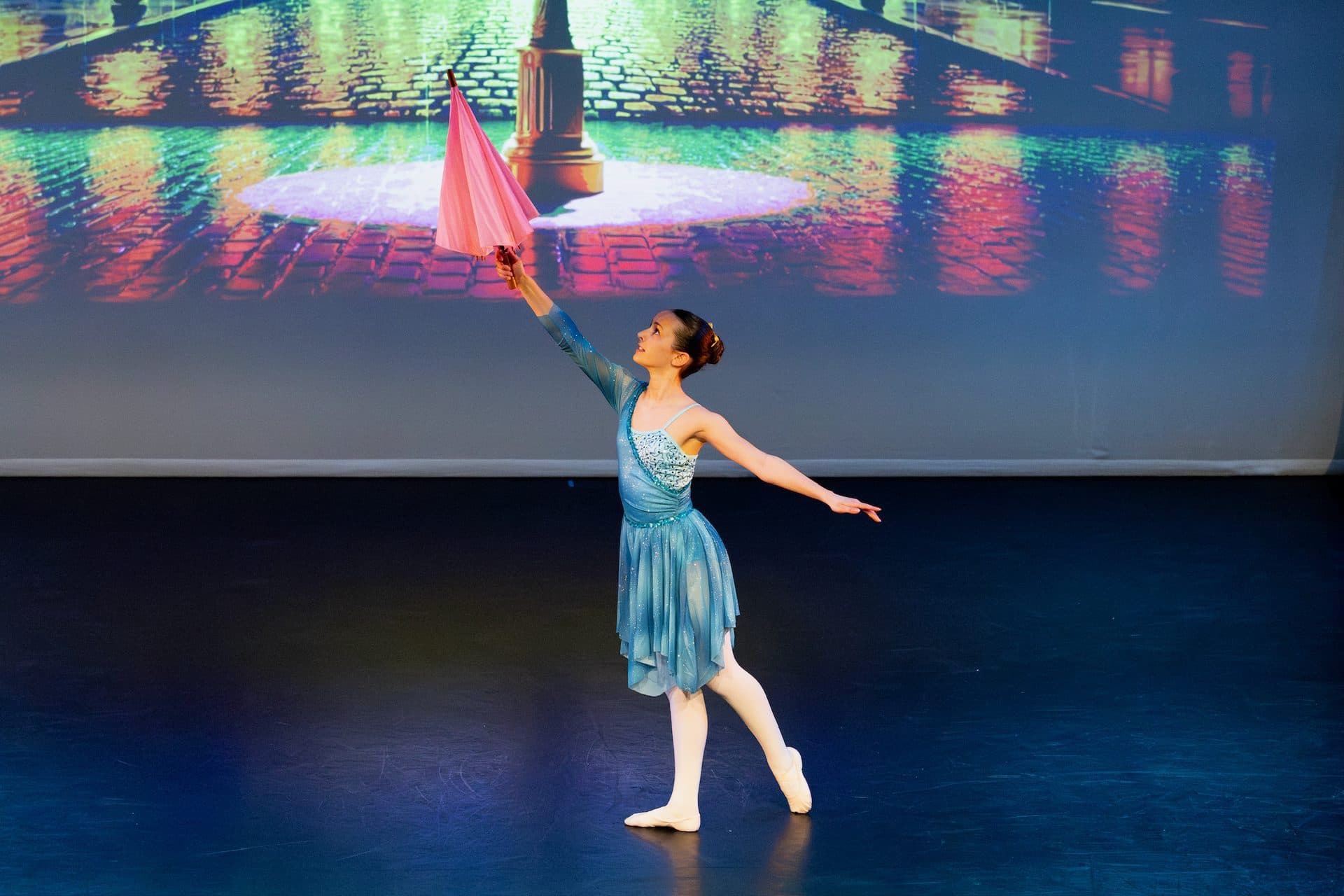 A ballet student performing with an umbrella on stage