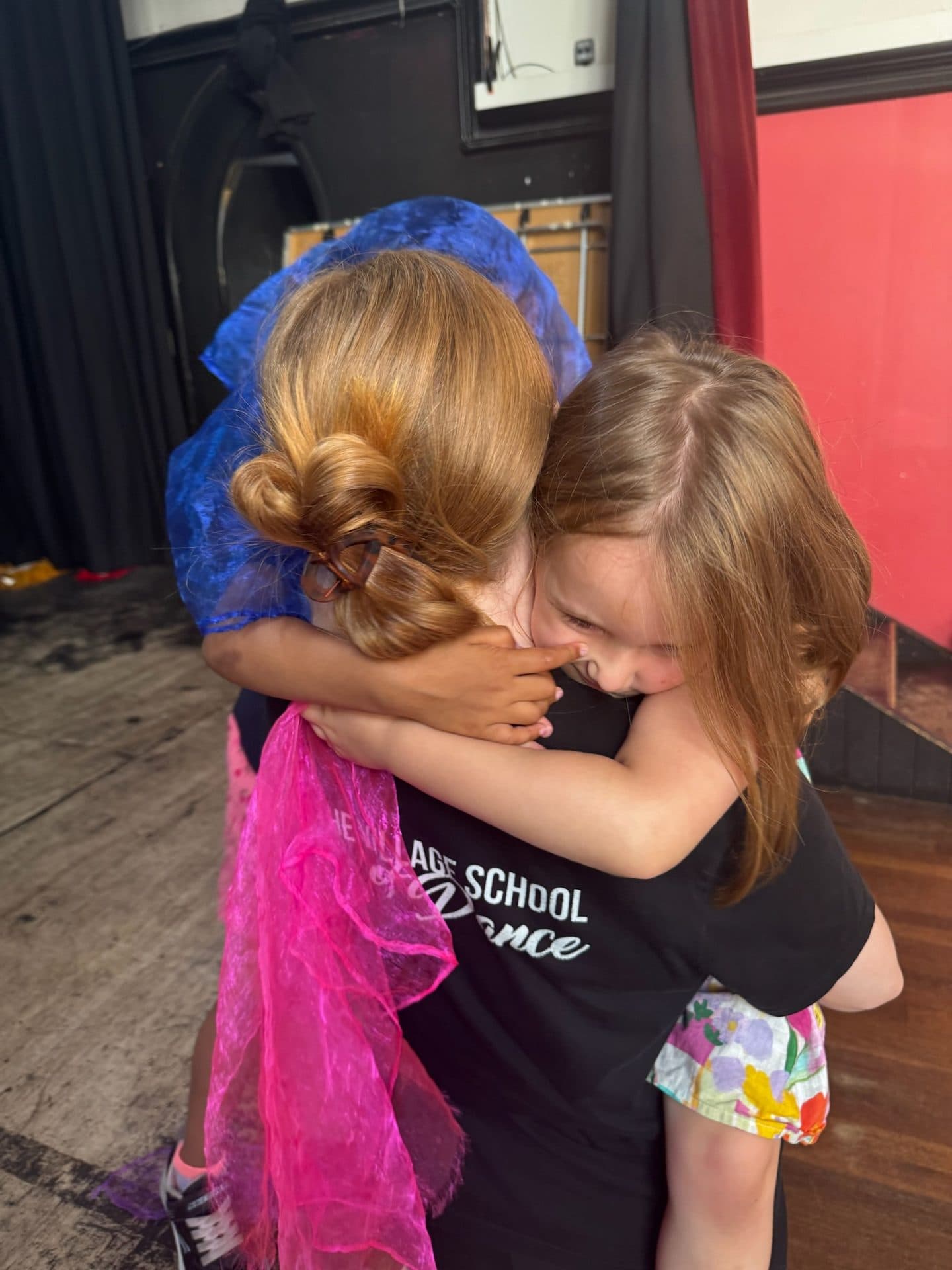 Two young dancers sharing a hug in a Wimbledon Village hall